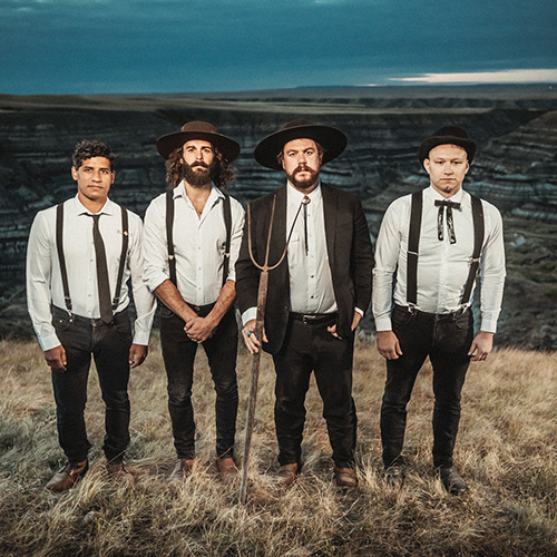 Photo des 4 membres du groupe THE DEAD SOUTH, prise en extérieure. Le groupe porte des tenues traditionnelle américaines.