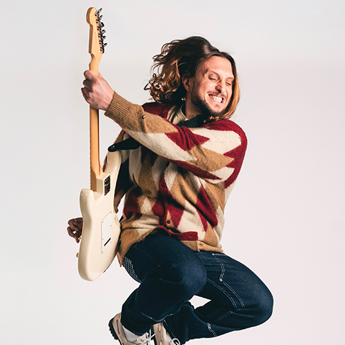 Photo de David (McFly) en plein saut avec sa guitare électrique.
