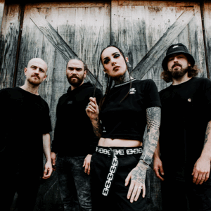 Photo des 5 membres du groupe Jinjer, devant une vieille porte en bois. Chaque membre fixe l'objectif et la photo est prise de bas.